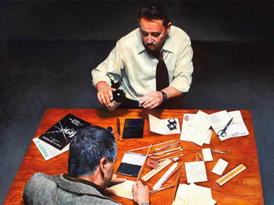 Two men sitting across from each other examining documents.